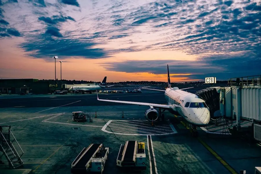 Airplane wing above the clouds at sunset